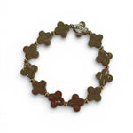 Gold bracelet with clover-shaped links on a white background