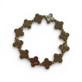 Gold bracelet with clover-shaped links on a white background