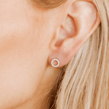 Close-up of an ear wearing a round hoop stud earring with a clear gemstone.