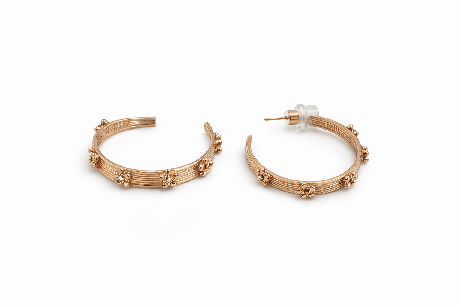A pair of gold hoop with flower detail earrings on a white background