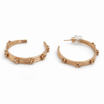 A pair of gold hoop with flower detail earrings on a white background