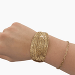 Gold bracelet on a wrist against a white background