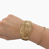 Gold bracelet on a wrist against a white background